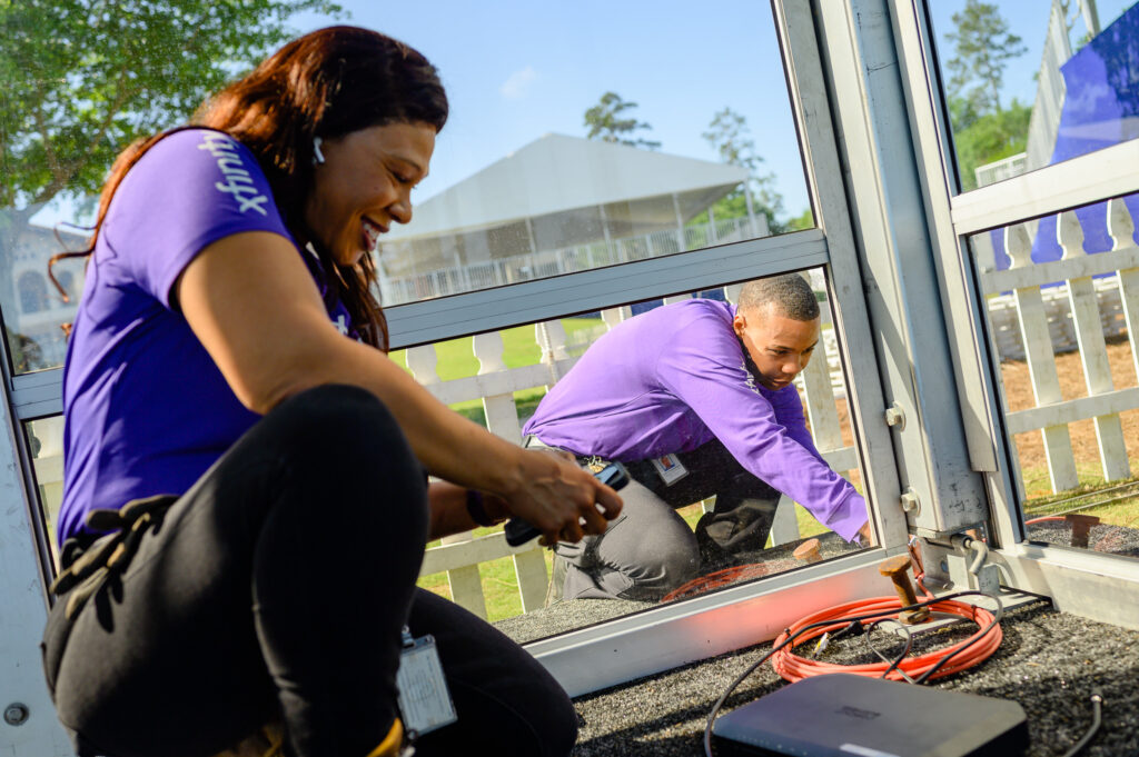 Two technicians working in tandem in near windows.