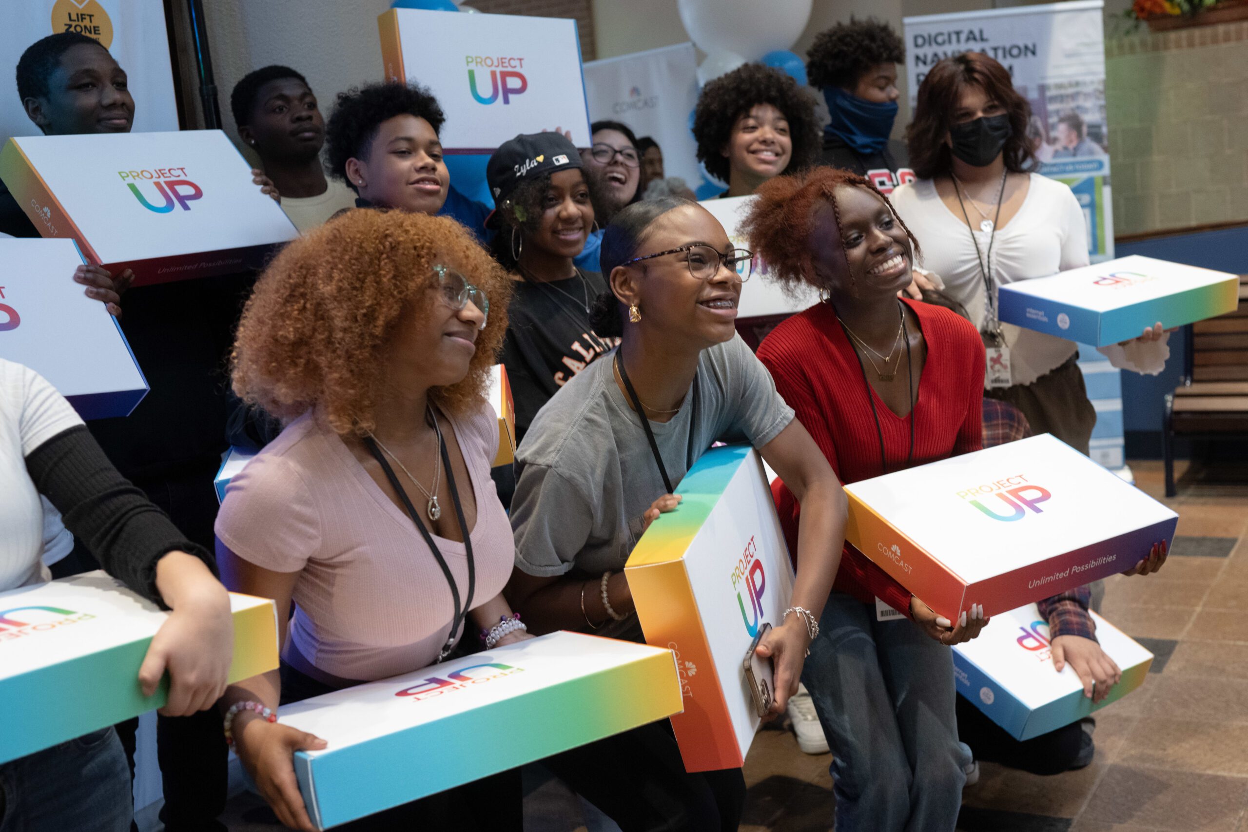 Group of young people holding laptop boxes and posing for a picture