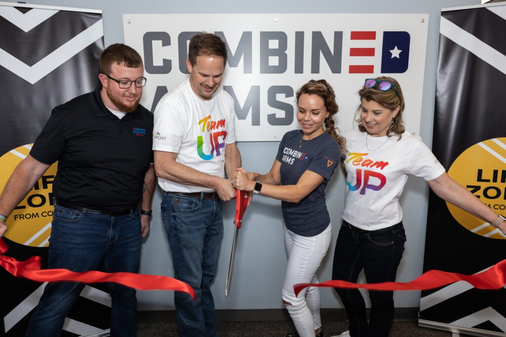 Group of people cutting red ribbon with large ceremonial scissor