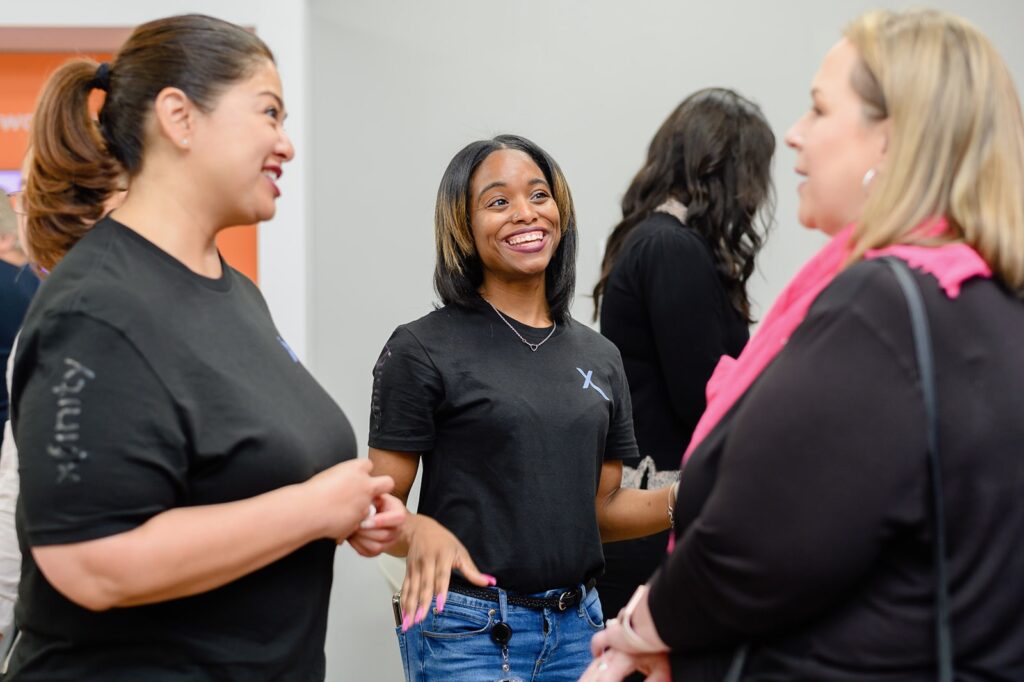 Three women standing together smiling and talking