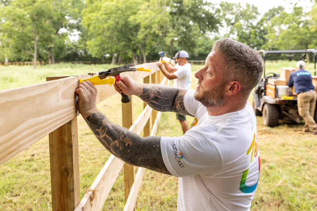 Team Up volunteer using hammer to repair fence