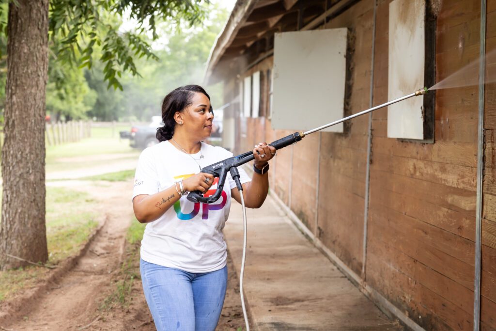 Female Team Up volunteer power washing side of barn