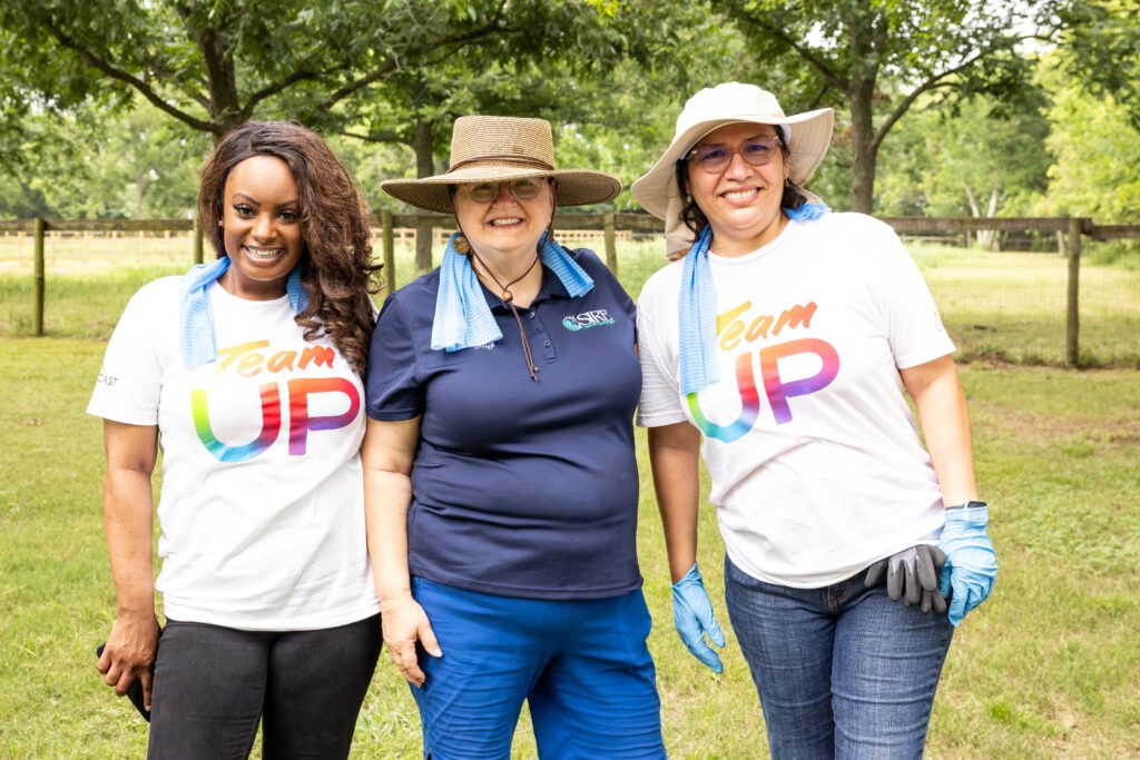 Three women posing for picture in field