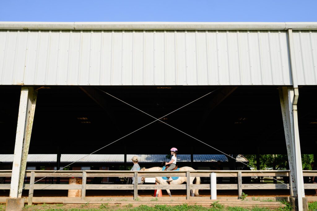 Young girl riding horse in stable