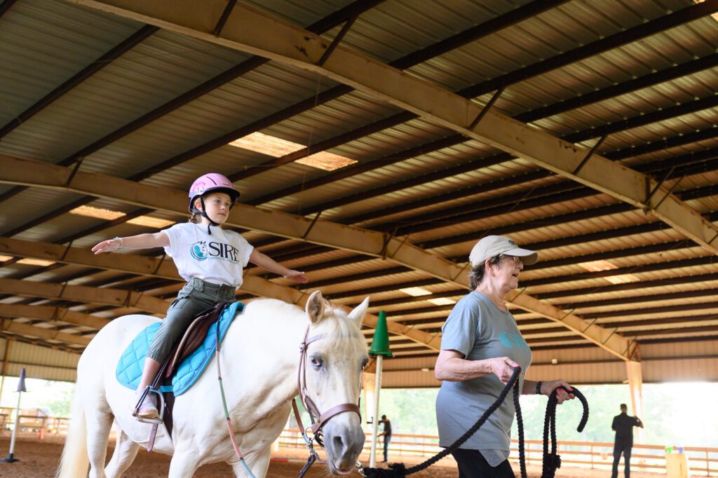 Young girl on horse with arms outstretched