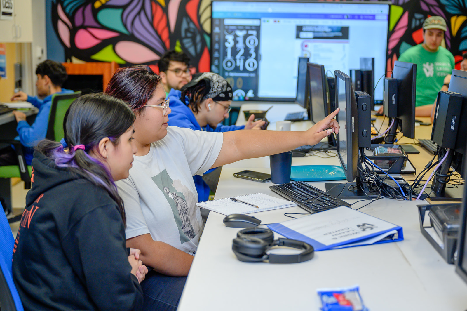 Two students work in front of a computer.