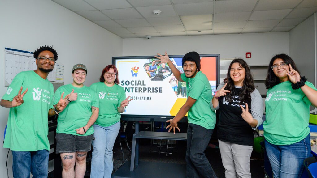 Students smile in front of their presentation.