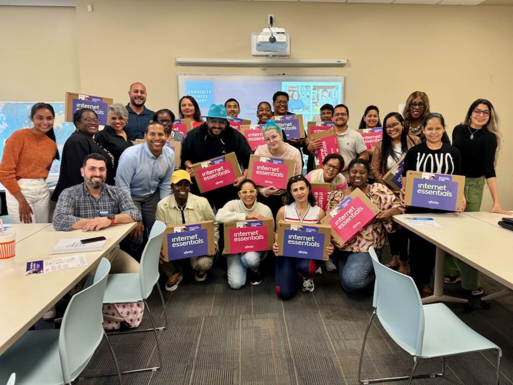 A group of people smile holding new laptops they received during Digital Inclusion Week.