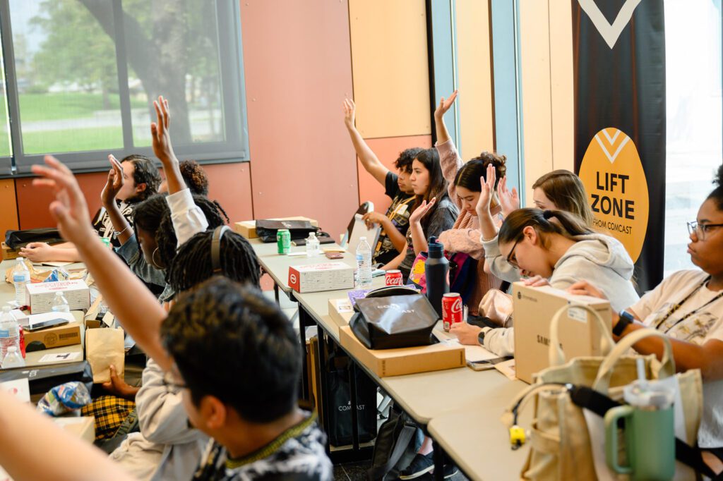 Students raise their hands with questions during the learning session.