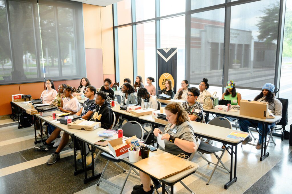 Students sit and listen to a presenter during the learning session.