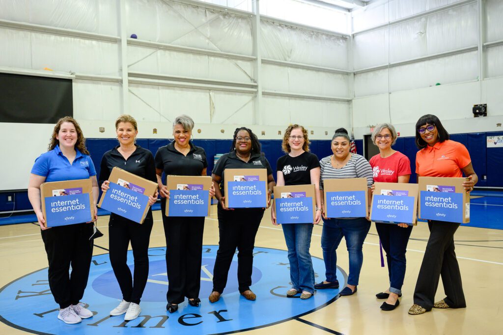 A group of people smile with new laptops during Digital Inclusion Week.